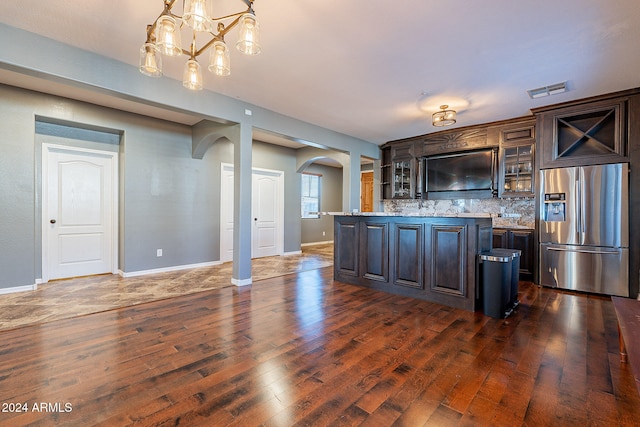 kitchen with pendant lighting, stainless steel refrigerator with ice dispenser, decorative backsplash, dark hardwood / wood-style floors, and dark brown cabinets