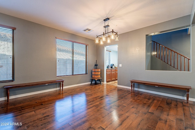 spare room featuring dark wood-type flooring and a notable chandelier