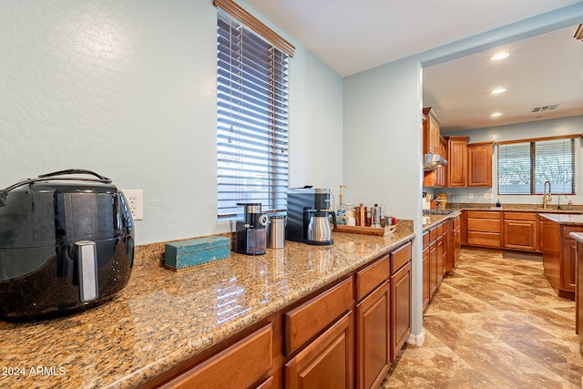 kitchen with a wealth of natural light, light stone counters, and stainless steel gas stovetop