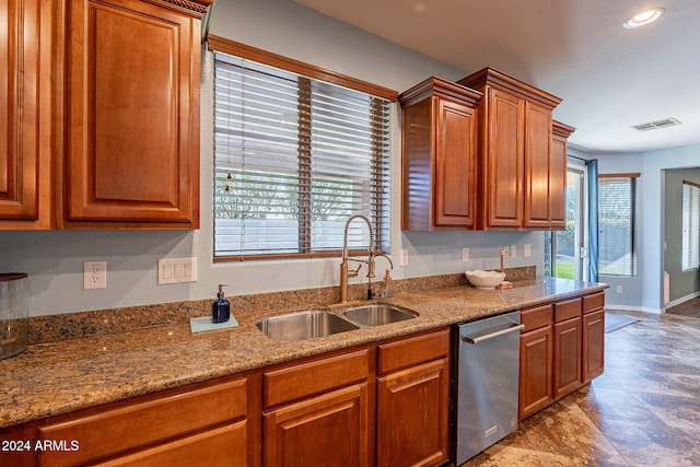 kitchen with stainless steel dishwasher, light stone countertops, a healthy amount of sunlight, and sink