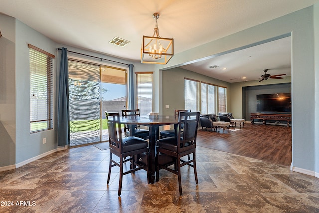 dining space with dark hardwood / wood-style flooring, a healthy amount of sunlight, and ceiling fan with notable chandelier