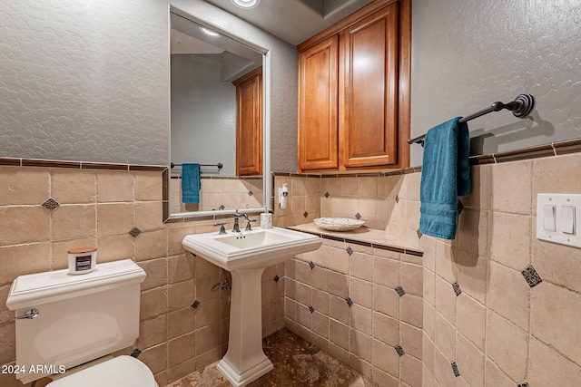 bathroom featuring toilet and tile walls