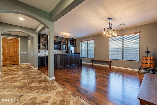 kitchen featuring dark brown cabinetry, dark hardwood / wood-style floors, hanging light fixtures, decorative backsplash, and a chandelier