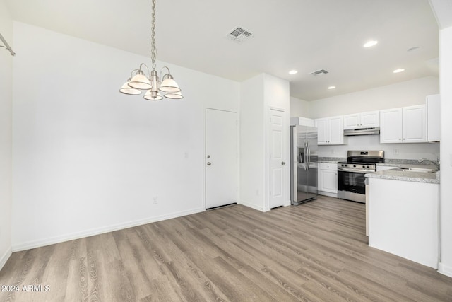 kitchen featuring stainless steel appliances, sink, pendant lighting, a chandelier, and white cabinetry