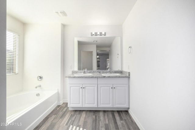 bathroom featuring ceiling fan, hardwood / wood-style floors, vanity, and a bath