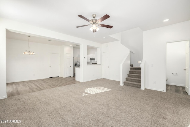 unfurnished living room with light carpet and ceiling fan with notable chandelier