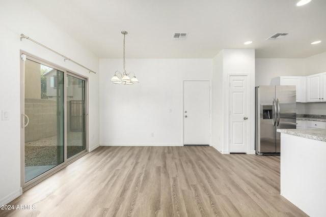 unfurnished dining area with light hardwood / wood-style floors and an inviting chandelier