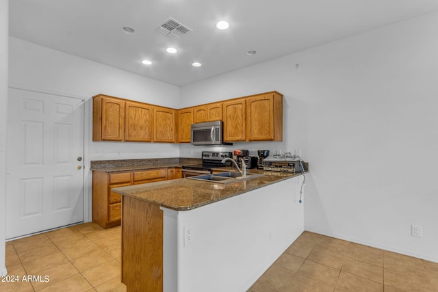 kitchen featuring stainless steel appliances, sink, kitchen peninsula, dark stone countertops, and light tile patterned flooring