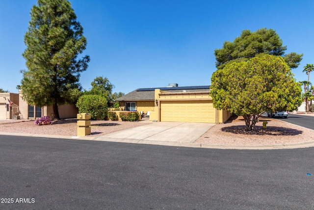 view of front of property featuring concrete driveway, an attached garage, roof mounted solar panels, and stucco siding