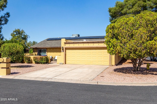 view of front of home with roof mounted solar panels, stucco siding, driveway, and a garage