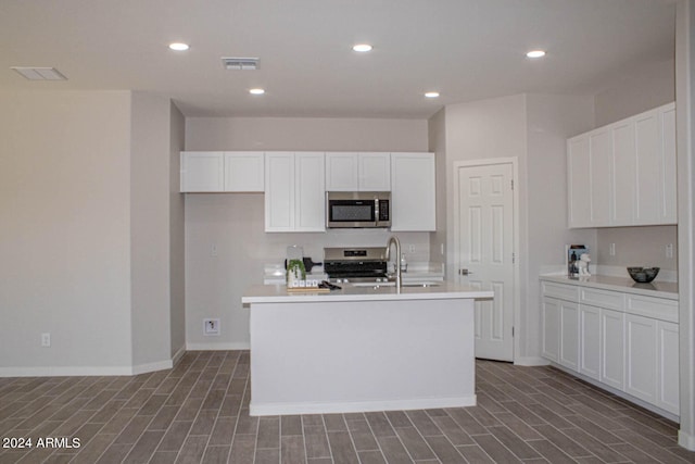 kitchen featuring white cabinets, appliances with stainless steel finishes, sink, and an island with sink