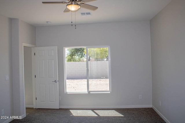 unfurnished room featuring a wealth of natural light, ceiling fan, and dark carpet