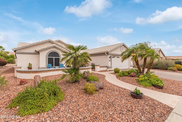 view of front facade featuring a garage, a tile roof, concrete driveway, and stucco siding