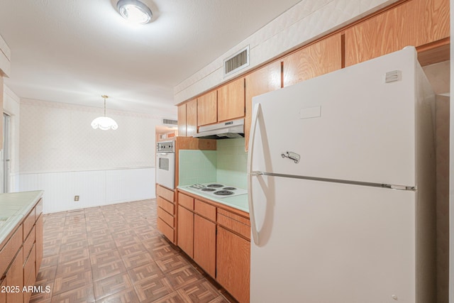 5228 E Des Moines St, Mesa, AZ 85205 - kitchen with white appliances, under cabinet range hood, wainscoting, tile countertops, and hanging light fixtures