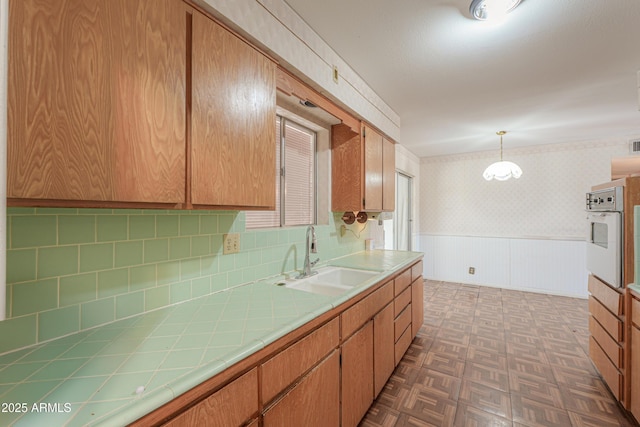5228 E Des Moines St, Mesa, AZ 85205 - kitchen with a sink, wallpapered walls, tile counters, oven, and a wainscoted wall