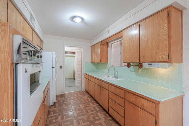 5228 E Des Moines St, Mesa, AZ 85205 - kitchen featuring a sink, white appliances, tasteful backsplash, wallpapered walls, and tile counters