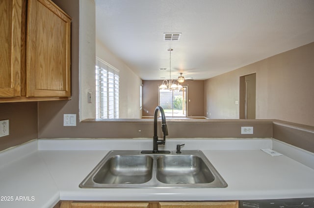 kitchen featuring visible vents, hanging light fixtures, a sink, light countertops, and a notable chandelier