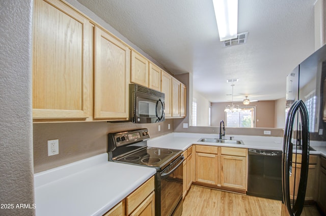 kitchen featuring light brown cabinets, black appliances, a sink, and visible vents