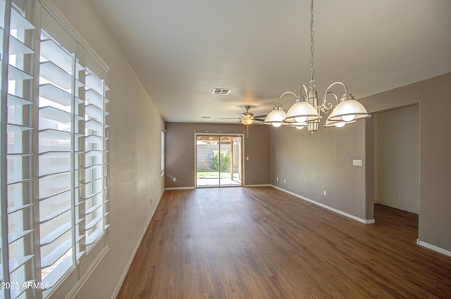 empty room featuring ceiling fan with notable chandelier, visible vents, baseboards, and wood finished floors