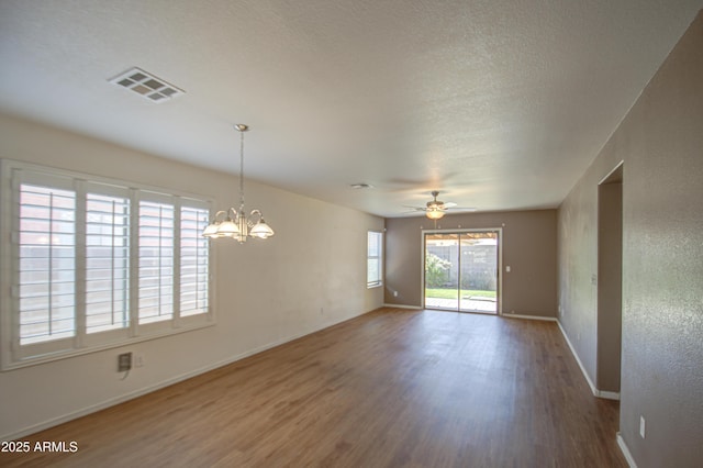 empty room featuring a textured ceiling, wood finished floors, visible vents, and baseboards