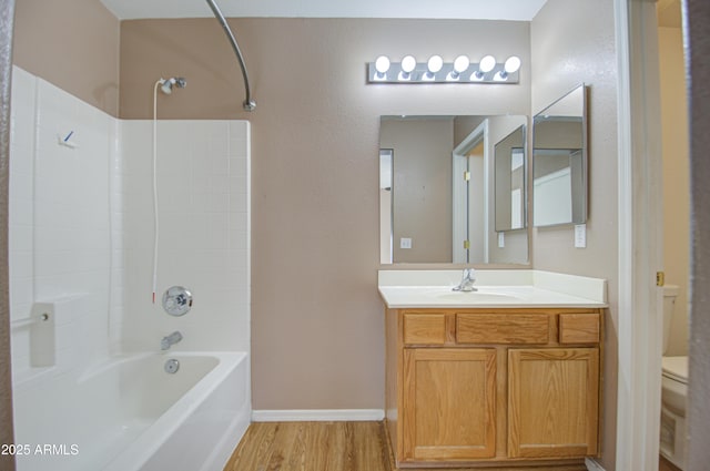 full bathroom with shower / bath combination, toilet, vanity, wood finished floors, and baseboards