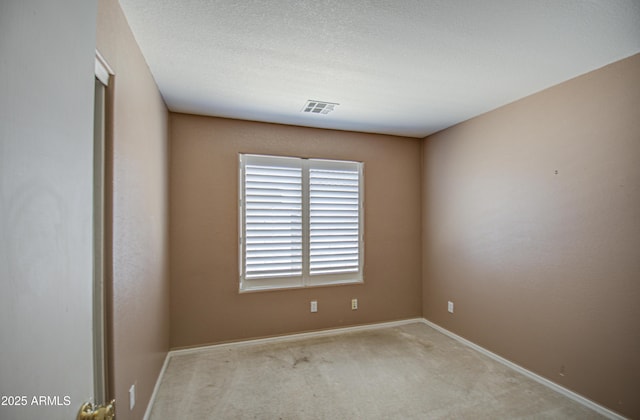 carpeted spare room featuring visible vents, a textured ceiling, and baseboards