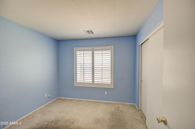 unfurnished bedroom featuring a closet, carpet, visible vents, and baseboards