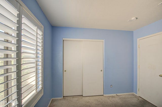 unfurnished bedroom with carpet, a closet, and baseboards