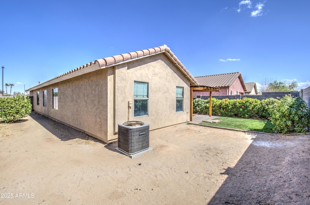 exterior space with cooling unit, fence, a tile roof, stucco siding, and a patio area