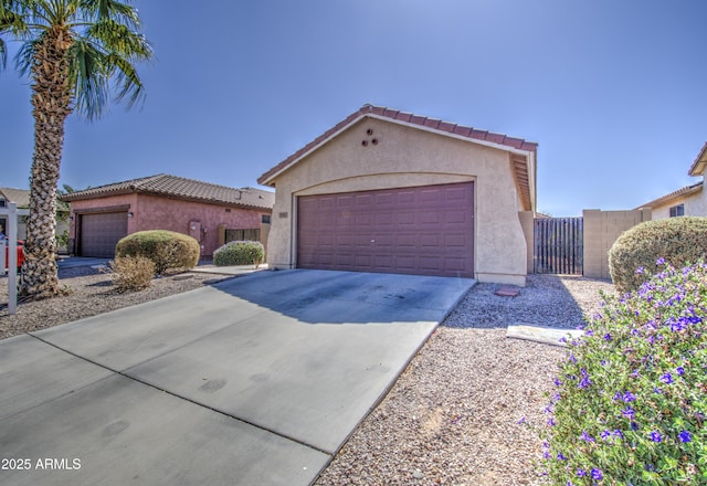 mediterranean / spanish home featuring an outdoor structure, fence, a tile roof, concrete driveway, and stucco siding