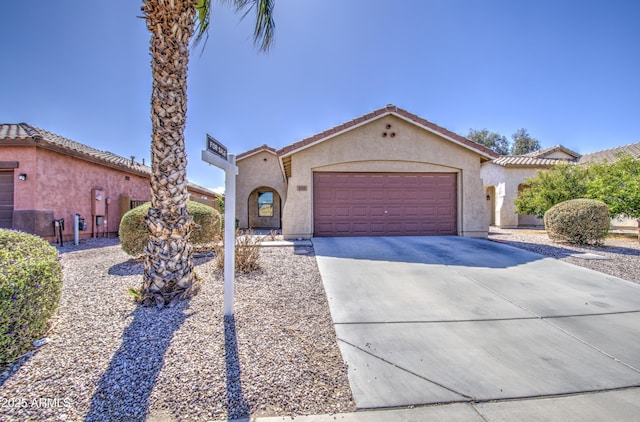 mediterranean / spanish home featuring concrete driveway, a tiled roof, an attached garage, and stucco siding