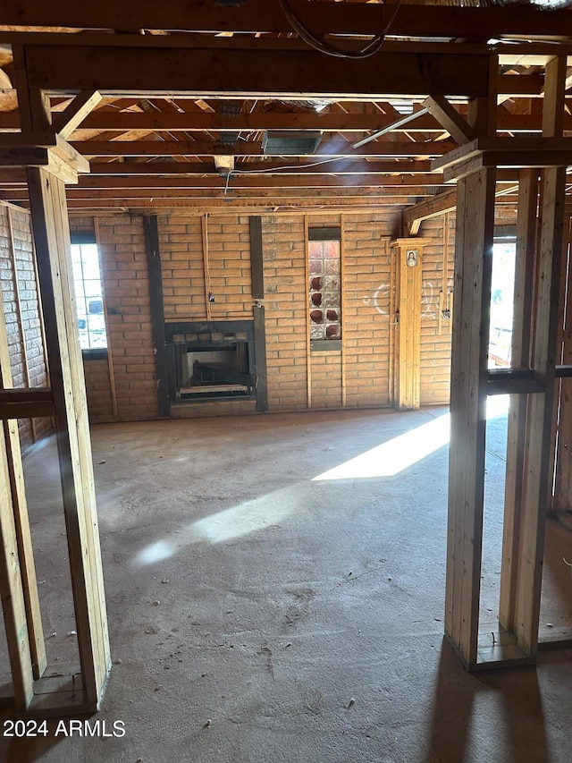 unfurnished living room featuring brick wall