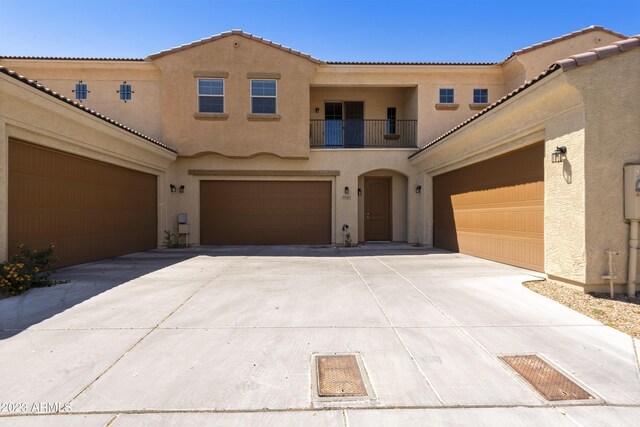 mediterranean / spanish home featuring stucco siding, a balcony, driveway, and a tiled roof