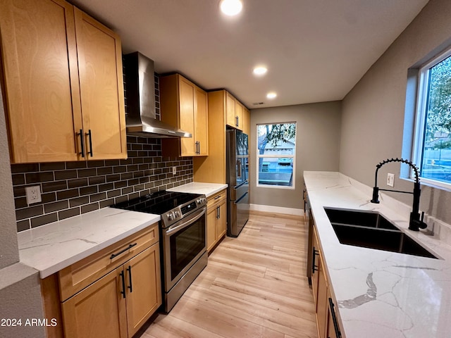 kitchen featuring light stone counters, sink, stainless steel range with electric cooktop, light hardwood / wood-style flooring, and wall chimney exhaust hood