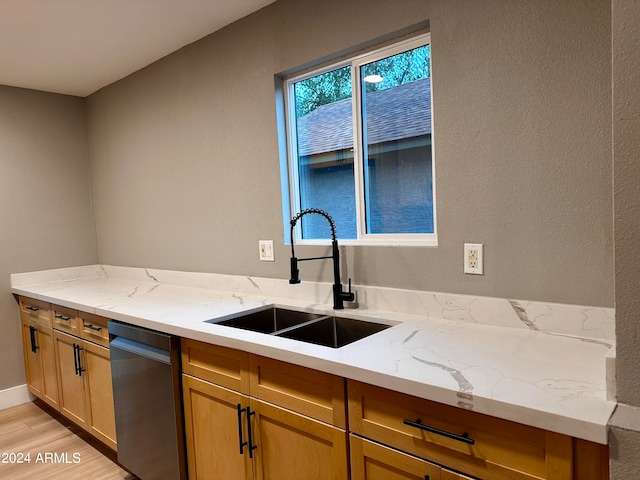 kitchen with light stone counters, dishwasher, light wood-type flooring, and sink