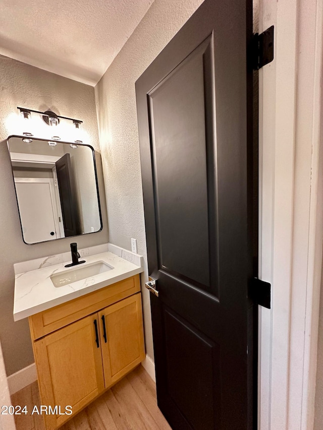 bathroom with a textured ceiling, wood-type flooring, and vanity