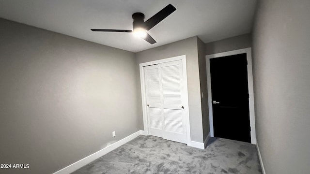 unfurnished bedroom featuring ceiling fan, light colored carpet, and a closet