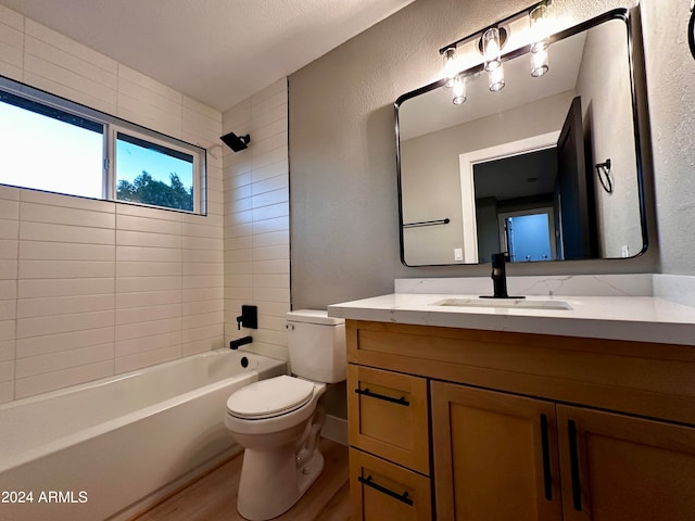 full bathroom with hardwood / wood-style flooring, tiled shower / bath combo, vanity, and toilet