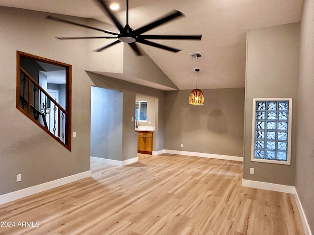 empty room with ceiling fan, light wood-type flooring, high vaulted ceiling, and a healthy amount of sunlight