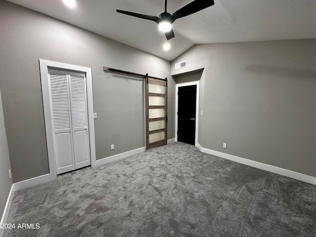 unfurnished bedroom featuring ceiling fan, lofted ceiling, carpet, a closet, and a barn door