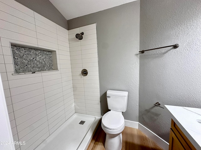 bathroom featuring toilet, vanity, hardwood / wood-style floors, and tiled shower