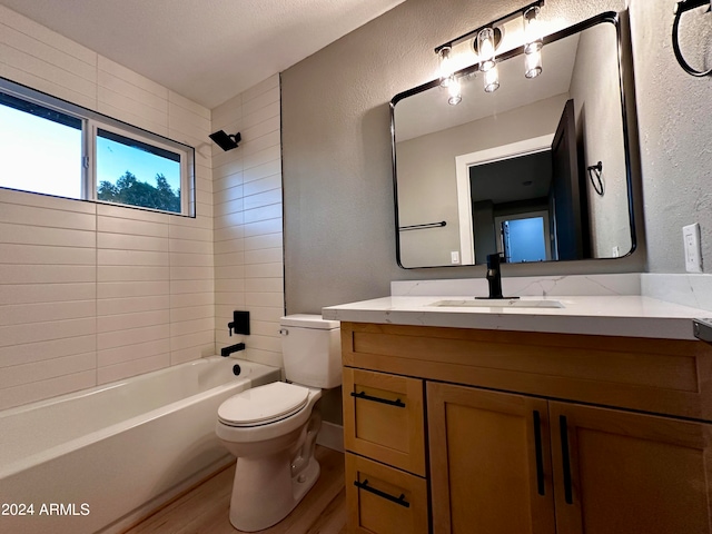 full bathroom featuring wood-type flooring, tiled shower / bath combo, vanity, and toilet