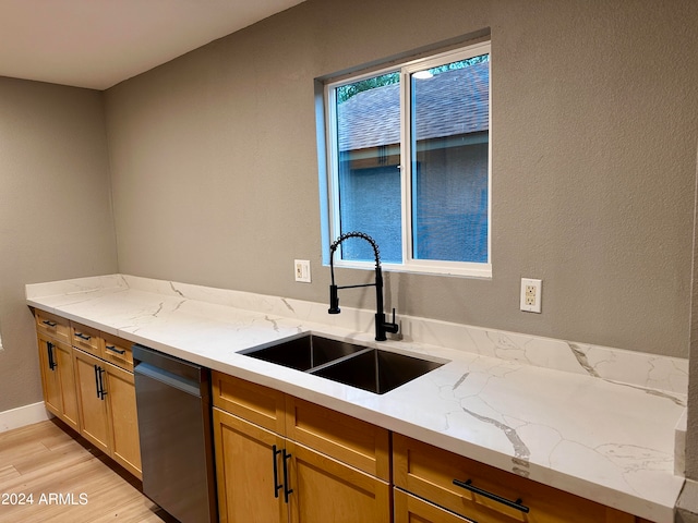 kitchen featuring light stone countertops, light wood-type flooring, sink, and stainless steel dishwasher