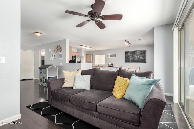 living room featuring baseboards, ceiling fan, and dark wood-style flooring