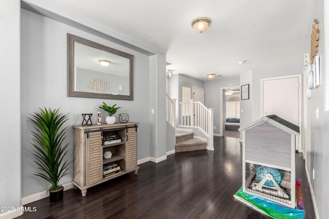 hallway featuring stairs, dark wood-type flooring, and baseboards