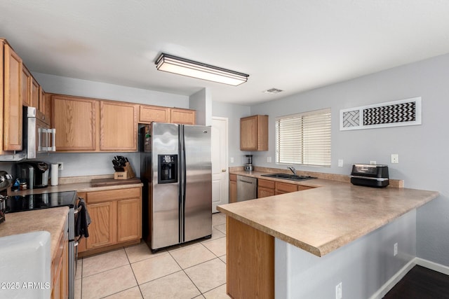 kitchen featuring a sink, stainless steel appliances, a peninsula, and light countertops