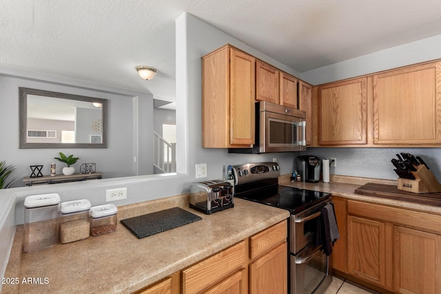 kitchen featuring light tile patterned floors, a toaster, stainless steel appliances, light countertops, and a textured ceiling