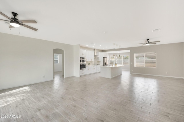 unfurnished living room with ceiling fan and light hardwood / wood-style flooring