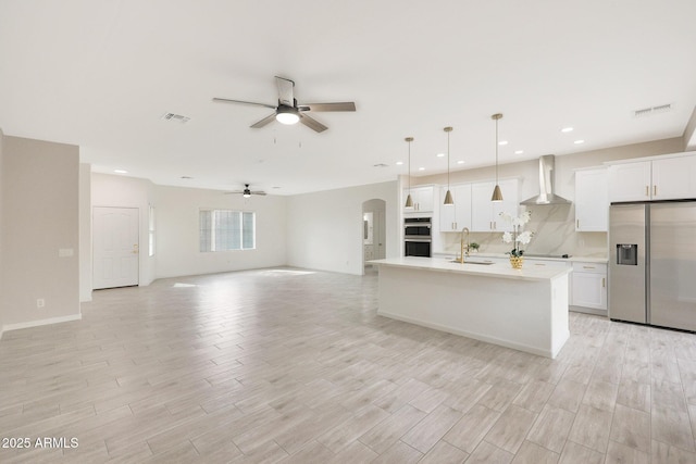 kitchen with sink, white cabinets, hanging light fixtures, stainless steel appliances, and wall chimney exhaust hood