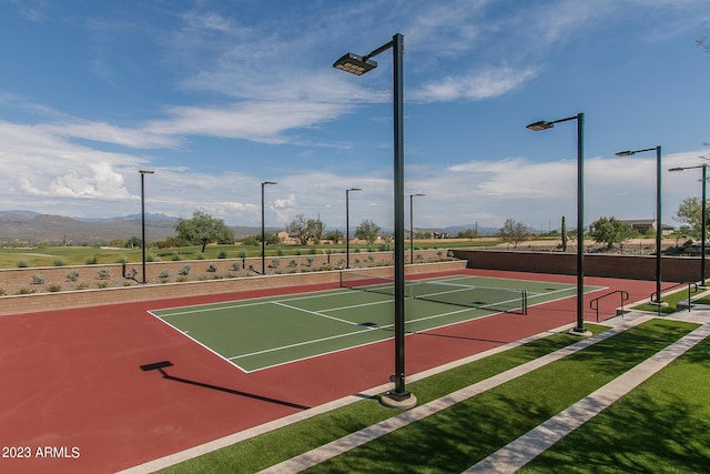 view of tennis court featuring basketball hoop and a mountain view